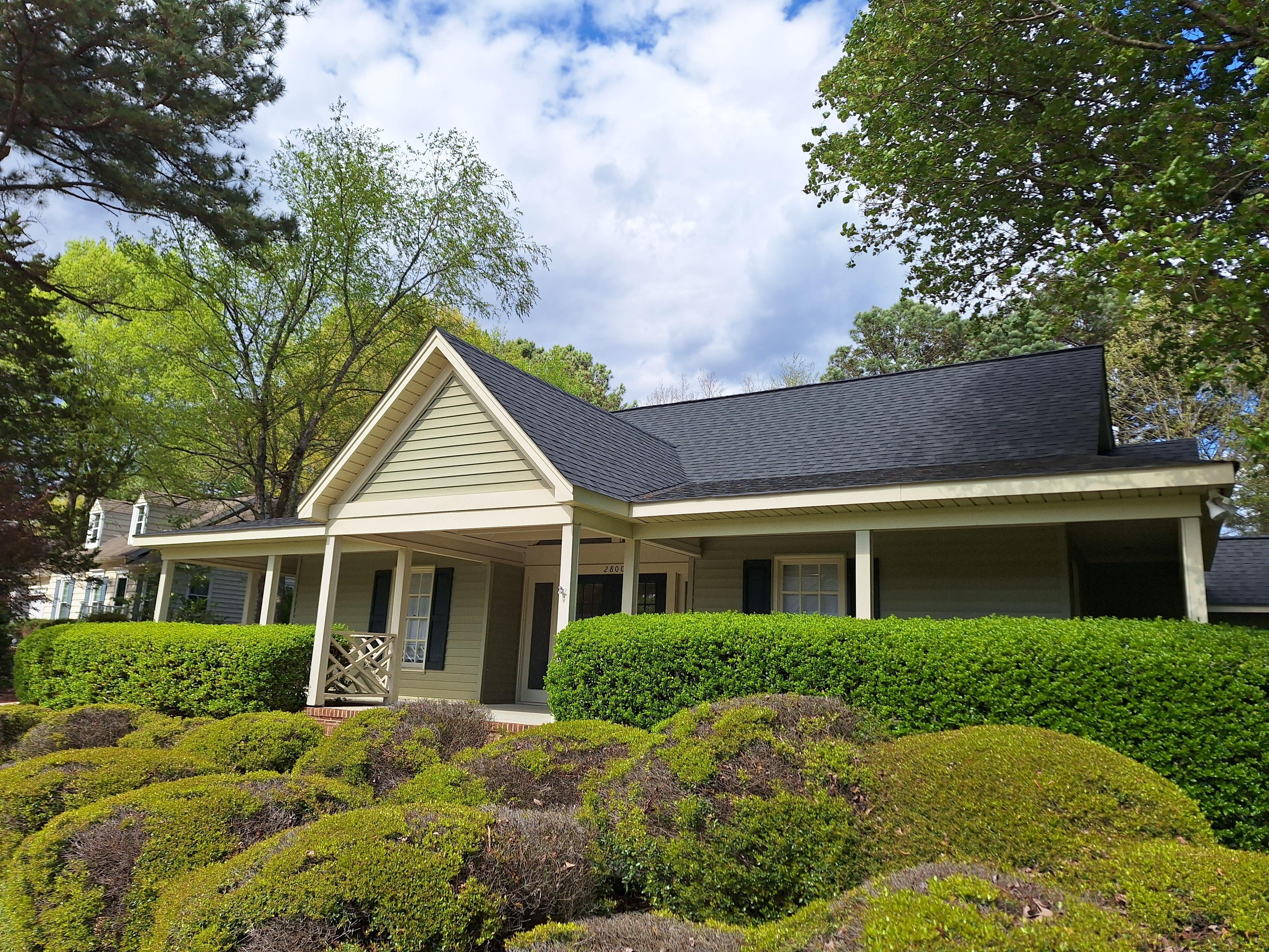 Well-maintained suburban house with manicured green bushes and porch